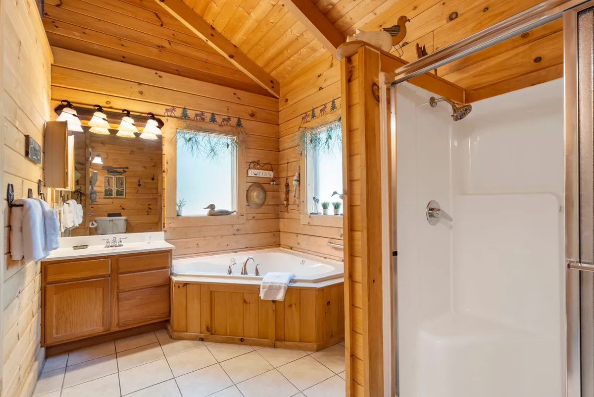 A spacious bathroom featuring a luxurious jacuzzi tub, surrounded by wooden accents and large mirrors. A glass shower stall is visible, creating a spa-like atmosphere ideal for relaxation after a long day.