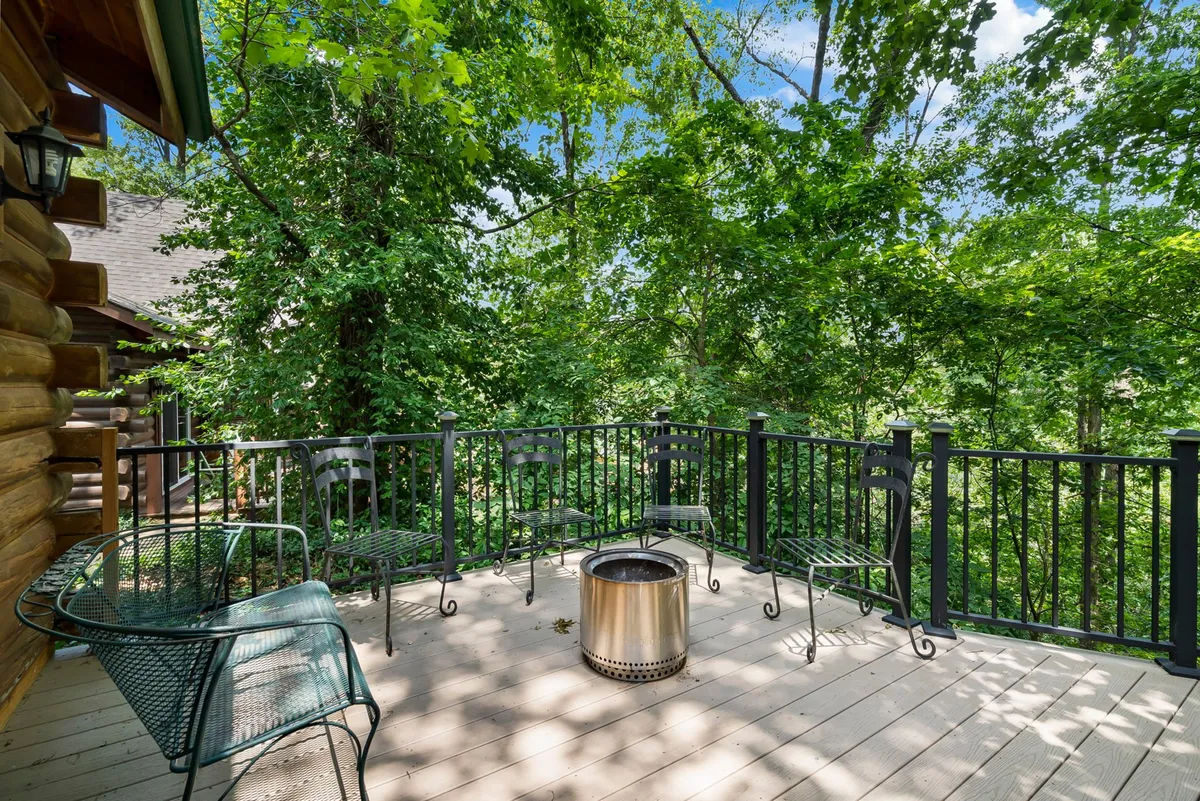 A cozy fire pit area set among trees, with deck seating nearby. The setup invites gatherings, storytelling, and evening relaxation. The fire pit and surrounding natural elements create a relaxing outdoor ambiance.